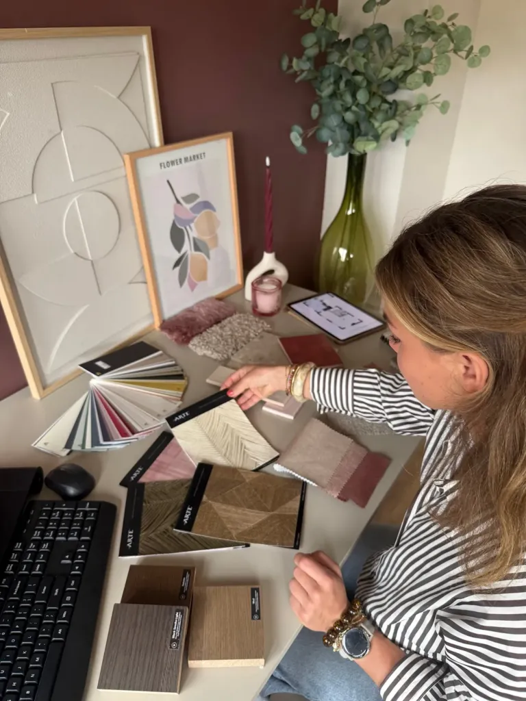 Interieurstylist van Studio Hulz bekijkt een plattegrond op een tablet tussen kleurstalen en stofstalen