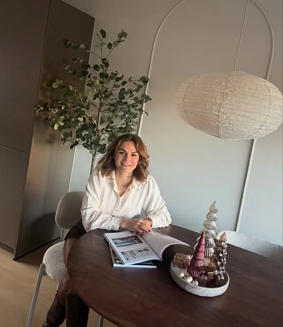 Vera Hulzebos, interieurstylist van Studio Hulz, aan een ronde eettafel met een interieurboek
